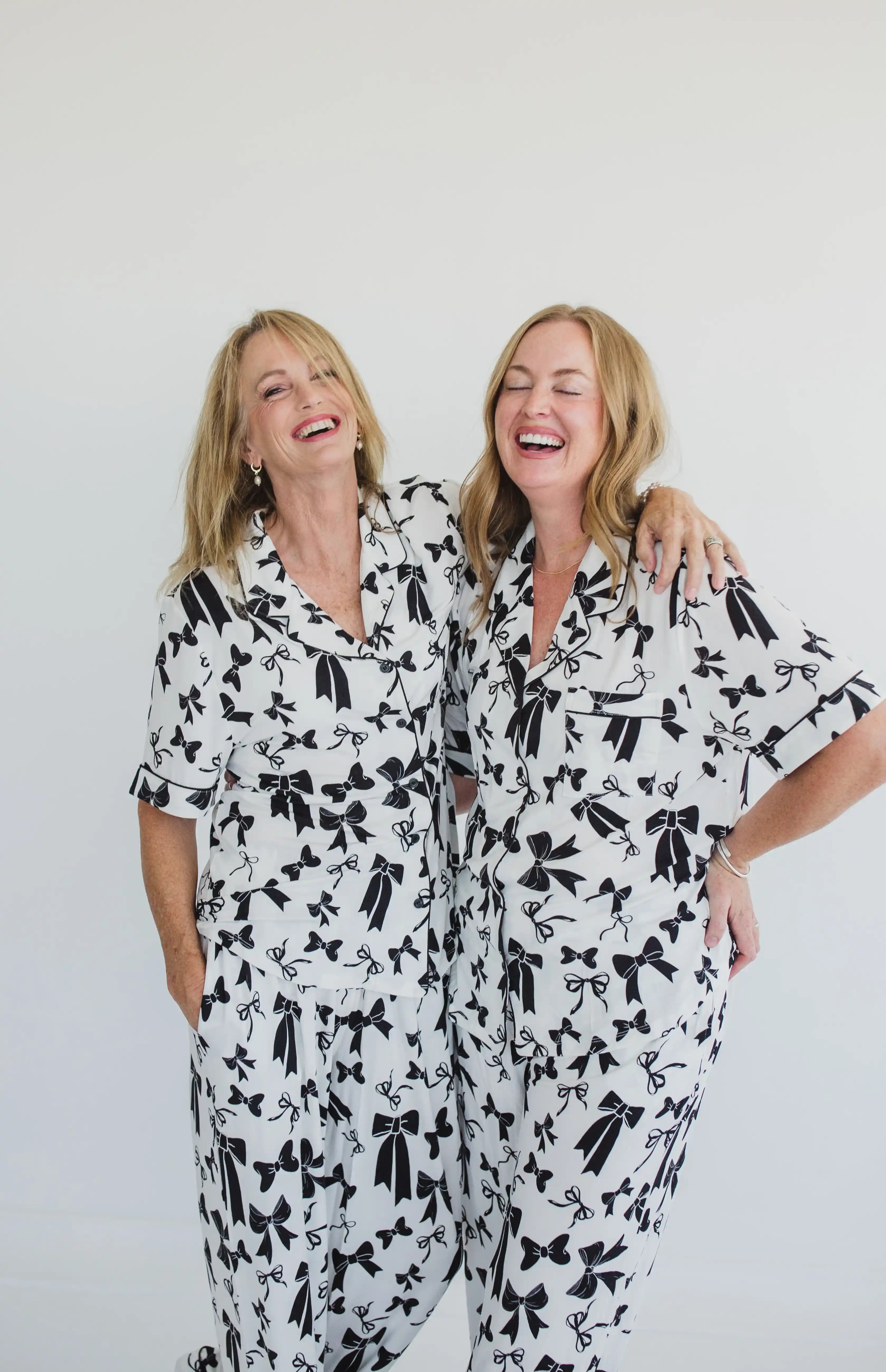 Two women wearing black and white patterned pajamas against a plain background